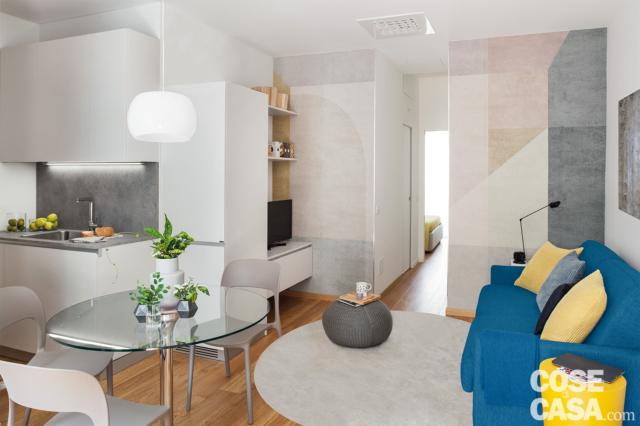 bilocale, zona conversazione, divano azzurro, tappeto bianco, tavolo con piano in vetro, sedie, angolo cottura, mobile tv bilocale, zona conversazione, divano azzurro, tappeto bianco, tavolo con piano in vetro, sedie, angolo cottura, mobile tv