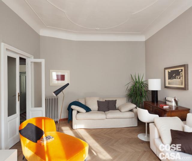 bilocale tradizionale, soggiorno, divani bianchi, chaise longue arancione, parquet a spina di pesce, porta in legno laccato bianco e vetro, soffitto con cornici decorative, postazione studio bilocale tradizionale, soggiorno, divani bianchi, chaise longue arancione, parquet a spina di pesce, porta in legno laccato bianco e vetro, soffitto con cornici decorative, postazione studio