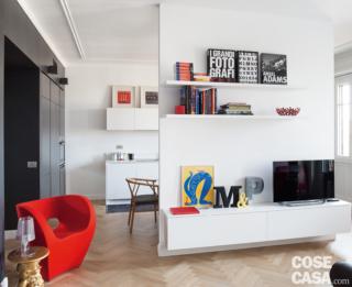 soggiorno, quinta, mobile tv sospeso in laccato bianco, ripiani, poltroncina rossa, parquet a spina di pesce, tavolino e lampada di design soggiorno, quinta, mobile tv sospeso in laccato bianco, ripiani, poltroncina rossa, parquet a spina di pesce, tavolino e lampada di design