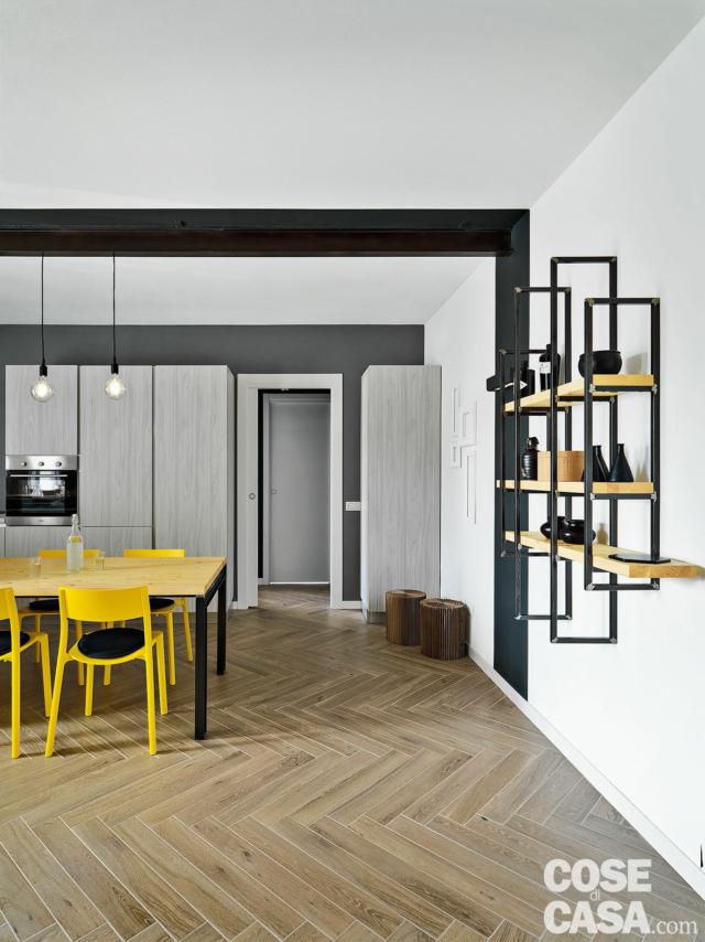 zona pranzo, tavolo, sedie gialle, lampade a bulbo, libreria sospesa in ferro e legno, pavimento in gres effetto parquet zona pranzo, tavolo, sedie gialle, lampade a bulbo, libreria sospesa in ferro e legno, pavimento in gres effetto parquet