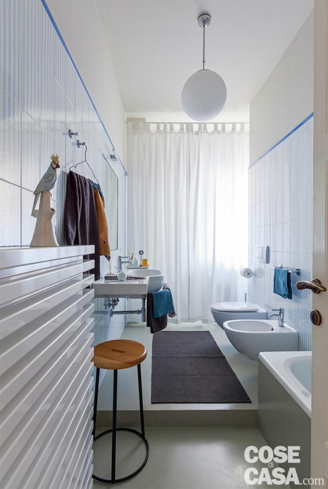 bagno lungo e stretto, gradino, rivestimenti in gres, finestra, lampada a sospensione sferica, scldasalviette, vasca, sanitari, sgabello tondo bagno lungo e stretto, gradino, rivestimenti in gres, finestra, lampada a sospensione sferica, scldasalviette, vasca, sanitari, sgabello tondo