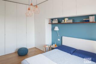 camera matrimoniale, letto con testiera bianca, armadio a ponte in laccato bianco, parete azzurra, applique, tavolino, sospensioni in finitura rame, pouf, pavimento in parquet camera matrimoniale, letto con testiera bianca, armadio a ponte in laccato bianco, parete azzurra, applique, tavolino, sospensioni in finitura rame, pouf, pavimento in parquet