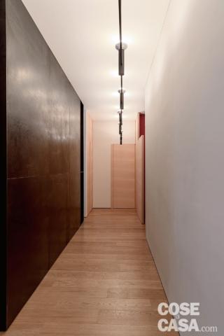 corridoio, parete grigia, pavimento in parquet, porta, sistema di faretti su binario sospeso corridoio, parete grigia, pavimento in parquet, porta, sistema di faretti su binario sospeso