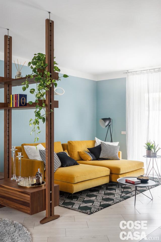 soggiorno, libreria passante, divano color senape, pareti azzurre, finestra, pavimento in gres, tappeto, lampada da terra soggiorno, libreria passante, divano color senape, pareti azzurre, finestra, pavimento in gres, tappeto, lampada da terra