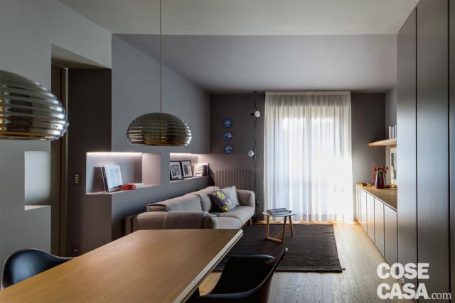 soggiorno aperto, parete attrezzata in laccato grigio, divano, portafinestra, tavolo da pranzo, sospensioni di design, pareti grigie, nicchie soggiorno aperto, parete attrezzata in laccato grigio, divano, portafinestra, tavolo da pranzo, sospensioni di design, pareti grigie, nicchie