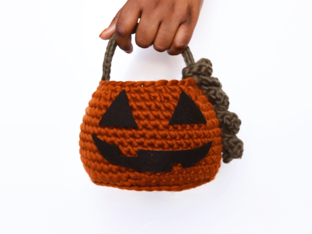 Una volta terminata la lavorazione della zucca, avrai due pezzi: il cesto con il manico e la foglia. Per rifinire, fai un nodo e nascondi i fili che restano inserendoli tra le maglie del lavoro, con l’aiuto dell’ago da lana. Una volta inseriti vari centimetri, taglia a filo con il tessuto. Fai un nodo con la foglia su uno dei lati del manico in modo che le estremità pendano su un lato. Con un pezzo di feltro nero, disegna due occhi e una bocca dando loro la forma che preferisci, e tagliali con le forbici. Infine, attacca gli occhi e la bocca con colla tessile sulla parte anteriore della zucca. Puoi fissare i pezzi con degli spilli finché la colla non sarà completamente asciutta. Una volta terminata la lavorazione della zucca, avrai due pezzi: il cesto con il manico e la foglia. Per rifinire, fai un nodo e nascondi i fili che restano inserendoli tra le maglie del lavoro, con l’aiuto dell’ago da lana. Una volta inseriti vari centimetri, taglia a filo con il tessuto. Fai un nodo con la foglia su uno dei lati del manico in modo che le estremità pendano su un lato. Con un pezzo di feltro nero, disegna due occhi e una bocca dando loro la forma che preferisci, e tagliali con le forbici. Infine, attacca gli occhi e la bocca con colla tessile sulla parte anteriore della zucca. Puoi fissare i pezzi con degli spilli finché la colla non sarà completamente asciutta.