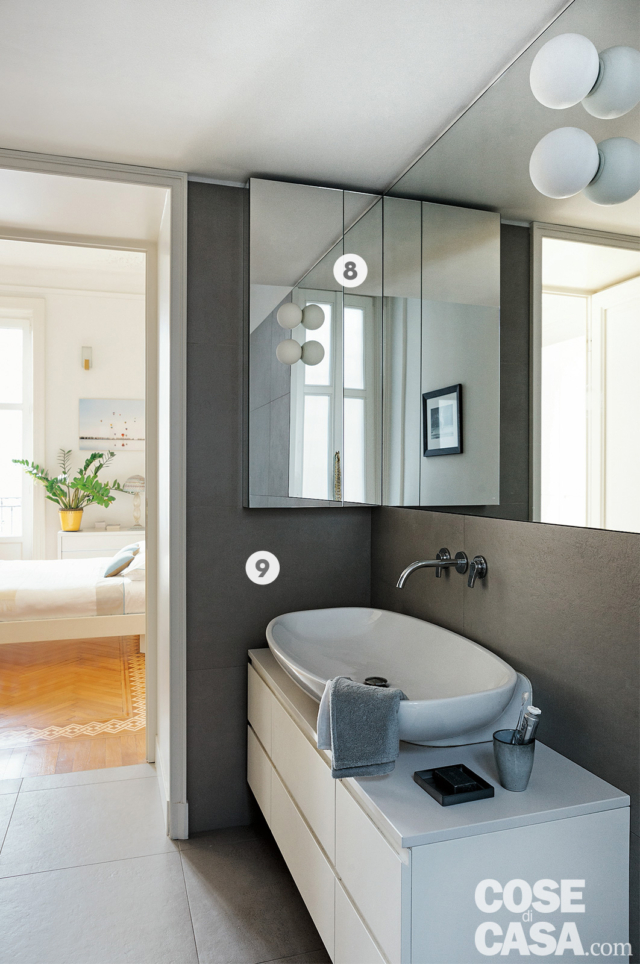bagno della casa d'epoca, pavimento in gres grigio, mobile sospeso, lavabo da appoggio, parete grigio scuro, specchio angolare, applique sferiche, rubinetto a parete bagno della casa d'epoca, pavimento in gres grigio, mobile sospeso, lavabo da appoggio, parete grigio scuro, specchio angolare, applique sferiche, rubinetto a parete