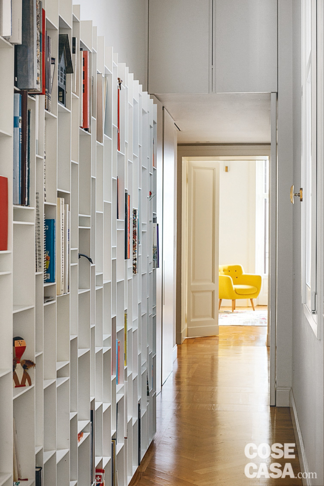 corridoio lungo e stretto, libreria componibile, finestra, parquet, porta in legno, poltroncina gialla corridoio lungo e stretto, libreria componibile, finestra, parquet, porta in legno, poltroncina gialla