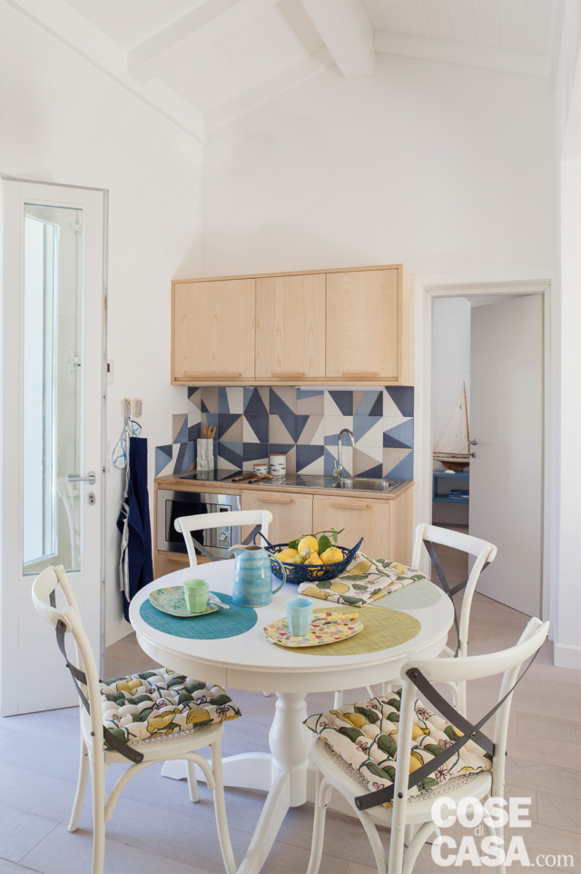 villa al mare, angolo cottura, mobili in legno di frassino, piastrelle decorate, tavolo da pranzo rotondo bianco, sedie bianche, portafinestra porta, pavimento in gres villa al mare, angolo cottura, mobili in legno di frassino, piastrelle decorate, tavolo da pranzo rotondo bianco, sedie bianche, portafinestra porta, pavimento in gres