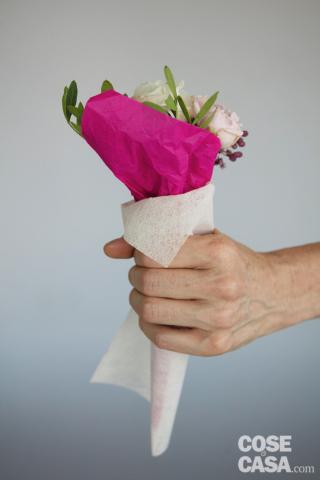 7.  Ripetere l’operazione con il tessuto non tessuto bianco, ma tenere il cono un poco più largo. Inserire nel cono il bouquet avvolto nella velina fucsia, tenendo il lembo esterno più alto dietro ai fiori, quindi ripiegarlo verso il basso. È importante che i coni nascondano alla perfezione gli steli e risultino anzi più lunghi di qualche centimetro,
in modo che, se necessario, si possano avvolgere
i gambi in una striscia di carta stagnola bagnata.
