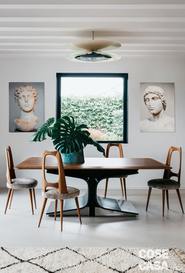 tavolo da pranzo con basamento centrale, sedie di design in legno, stampe appese, lampada a soffitto, tappeto tavolo da pranzo con basamento centrale, sedie di design in legno, stampe appese, lampada a soffitto, tappeto