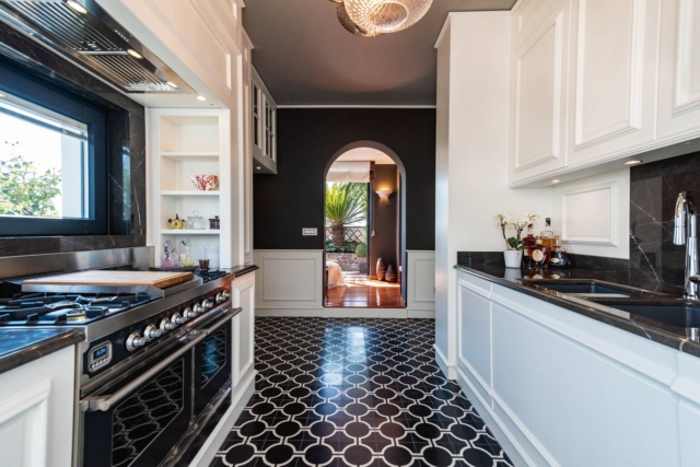 Cucina della casa ristrutturata in stile classico moderno, vista sulla zona operativa, con doppio piano cottura e forno. Mobili con finitura bianca e inserti neri. A pavimento cementine black & white. Cucina della casa ristrutturata in stile classico moderno, vista sulla zona operativa, con doppio piano cottura e forno. Mobili con finitura bianca e inserti neri. A pavimento cementine black & white.