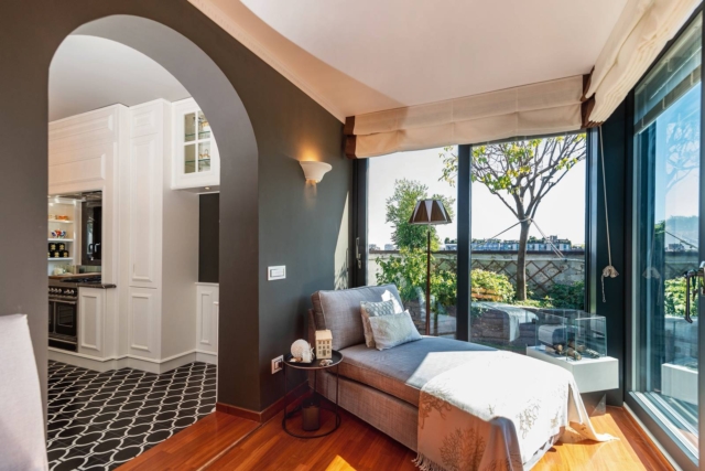 Veranda casa ristrutturata in stile classico moderno, arco parete grigia parquet e pavimento decorato bianco e nero. Chaise longue grigia, tavolino in metallo nero e applique bianca. Tende a pacchetto. Veranda casa ristrutturata in stile classico moderno, arco parete grigia parquet e pavimento decorato bianco e nero. Chaise longue grigia, tavolino in metallo nero e applique bianca. Tende a pacchetto.