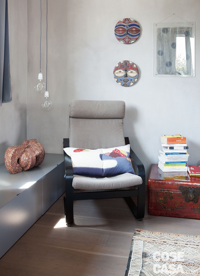 poltrona rivestita in tessuto grigio, lampade a sospensione con bulbo trasparente, tavolino, mobile basso, parquet, tappeto poltrona rivestita in tessuto grigio, lampade a sospensione con bulbo trasparente, tavolino, mobile basso, parquet, tappeto