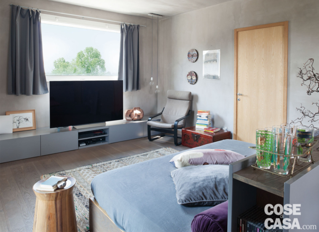 soggiorno cucina con porta ingresso, finestra a nastro, zona tv, mobile basso, divano-letto, poltrona, tavolino in legno grezzo, tappeto, pavimento in parquet, mobile divisorio con piano d'appoggio soggiorno cucina con porta ingresso, finestra a nastro, zona tv, mobile basso, divano-letto, poltrona, tavolino in legno grezzo, tappeto, pavimento in parquet, mobile divisorio con piano d'appoggio