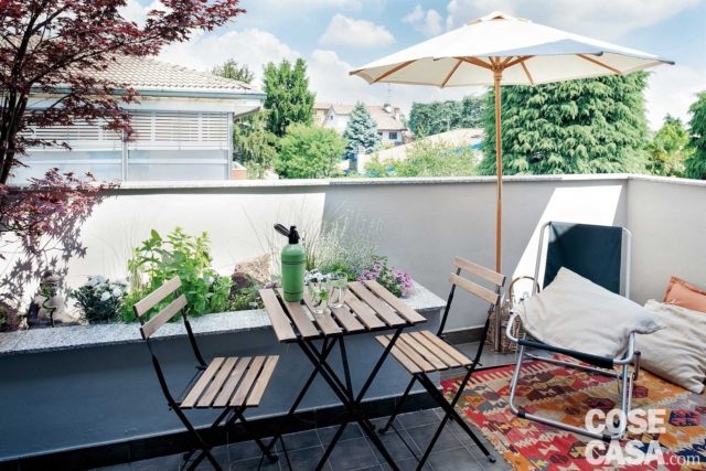 balcone del mini appartamento, fioriera in cemento, tavolino e sedie pieghevoli, sdraio, cuscini, ombrellone bianco balcone del mini appartamento, fioriera in cemento, tavolino e sedie pieghevoli, sdraio, cuscini, ombrellone bianco