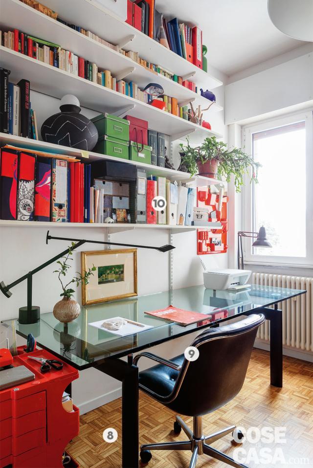 studio del trilocale, ripiani bianchi, scrivania con piano in vetro, sedia con ruote, lampada da tavolo a braccio orientabile, finestra, radiatore, carrello rosso, pavimento in parquet studio del trilocale, ripiani bianchi, scrivania con piano in vetro, sedia con ruote, lampada da tavolo a braccio orientabile, finestra, radiatore, carrello rosso, pavimento in parquet