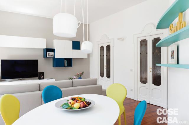 soggiorno, zona pranzo, tavolo bianco, sedie gialle e blu, lampade a sospensione bianche, ripiani colorati, divano, zona tv, pensili in laccato bianco, porte d'epoca in legno e vetro decorato soggiorno, zona pranzo, tavolo bianco, sedie gialle e blu, lampade a sospensione bianche, ripiani colorati, divano, zona tv, pensili in laccato bianco, porte d'epoca in legno e vetro decorato