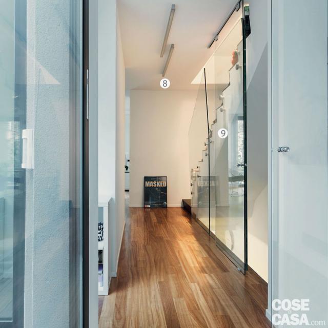 8. Luce naturale e artificiale
Tra gli obiettivi del relooking dell’appartamento vi era quello di valorizzare al massimo la doppia esposizione. Ma anche il progetto illuminotecnico ha una grande rilevanza nel risultato finale. Sono stati riutilizzati e valorizzati da cambi di posizione alcuni corpi illuminanti già esistenti (come le barre led a soffitto nel corridoio d’ingresso) e ne sono stati inseriti altri disegnati dal padrone di casa (faretti e applique). In camera, la zona sopra il letto è illuminata dalla luce diffusa che filtra da una “tasca” in metallo incassata nel muro.
9. Il parapetto trasparente
La rampa che dall’atrio al piano terra porta a quello principale della casa è in linea rispetto a quella che sale al piano superiore. Una struttura formata da lastre in vetro temperato trasparente costituisce il parapetto di sicurezza che, fissato al corpo scala con imbullonature metalliche, ne delimita esternamente il volume. La soluzione integra anche il sistema che chiude il vano d’accesso alla rampa di discesa:un pannello scorrevole a tutta altezza, sempre in vetro trasparente, appeso al binario metallico in alto. 8. Luce naturale e artificiale
Tra gli obiettivi del relooking dell’appartamento vi era quello di valorizzare al massimo la doppia esposizione. Ma anche il progetto illuminotecnico ha una grande rilevanza nel risultato finale. Sono stati riutilizzati e valorizzati da cambi di posizione alcuni corpi illuminanti già esistenti (come le barre led a soffitto nel corridoio d’ingresso) e ne sono stati inseriti altri disegnati dal padrone di casa (faretti e applique). In camera, la zona sopra il letto è illuminata dalla luce diffusa che filtra da una “tasca” in metallo incassata nel muro.
9. Il parapetto trasparente
La rampa che dall’atrio al piano terra porta a quello principale della casa è in linea rispetto a quella che sale al piano superiore. Una struttura formata da lastre in vetro temperato trasparente costituisce il parapetto di sicurezza che, fissato al corpo scala con imbullonature metalliche, ne delimita esternamente il volume. La soluzione integra anche il sistema che chiude il vano d’accesso alla rampa di discesa:un pannello scorrevole a tutta altezza, sempre in vetro trasparente, appeso al binario metallico in alto.