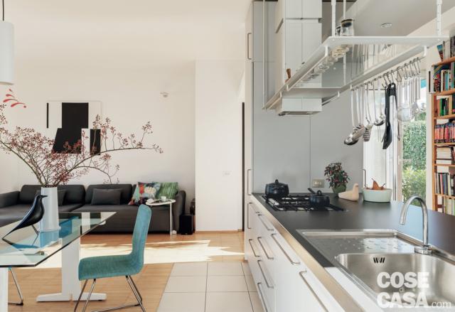 soggiorno con spazi aperti, cucina a isola, cappa, tavolo da pranzo con piano in vetro, sedia azzurra, uccellino, vaso, divano in pelle soggiorno con spazi aperti, cucina a isola, cappa, tavolo da pranzo con piano in vetro, sedia azzurra, uccellino, vaso, divano in pelle