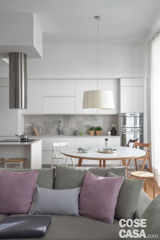 cucina, cappa cilindrica in acciaio, zona cottura, tavolo da pranzo rotondo, sedie pieghevoli, lampada a sospensione, basi e pensili, colonna forni, divano, cuscini rosa e grigi cucina, cappa cilindrica in acciaio, zona cottura, tavolo da pranzo rotondo, sedie pieghevoli, lampada a sospensione, basi e pensili, colonna forni, divano, cuscini rosa e grigi