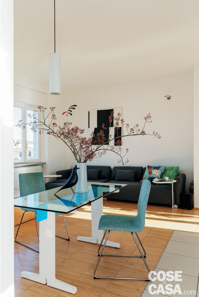 soggiorno, tavolo con piano in vetro, sedie azzurre, vaso, uccellino, parquet industriale, lampada bianca a sospensione, finestra soggiorno, tavolo con piano in vetro, sedie azzurre, vaso, uccellino, parquet industriale, lampada bianca a sospensione, finestra