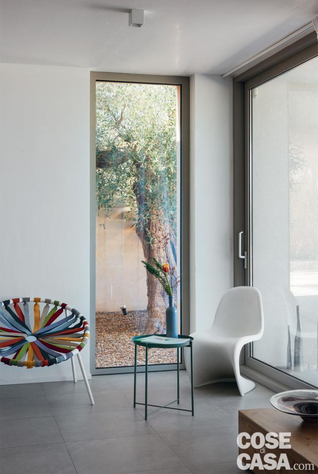 vetrate, patio, ghiaia a terra, albero di ulivo, sedia di design, poltroncina con seduta elastica, tavolino rotondo, pavimento in gres, faretti vetrate, patio, ghiaia a terra, albero di ulivo, sedia di design, poltroncina con seduta elastica, tavolino rotondo, pavimento in gres, faretti