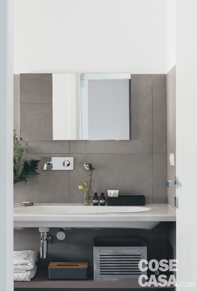 bagno, parete rivestita in gres grigio, piano sospeso, lavabo, miscelatore a parete, piano d'appoggio inferiore, porta bagno, parete rivestita in gres grigio, piano sospeso, lavabo, miscelatore a parete, piano d'appoggio inferiore, porta