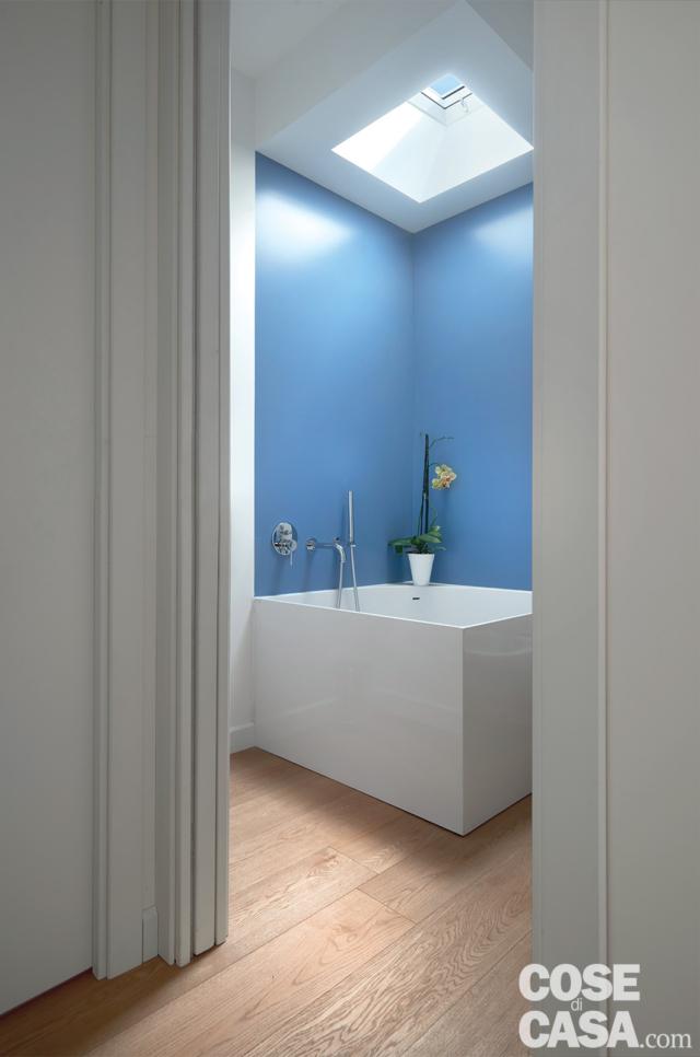 Bagno con vasca freestanding illuminata da finestra sul tetto piano parquet Bagno con vasca freestanding illuminata da finestra sul tetto piano parquet
