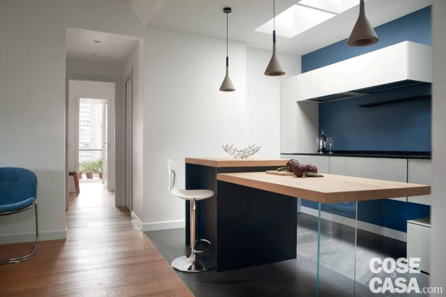 Cucina a vista sul soggiorno con banco snack, parquet e resina grigia a pavimento Cucina a vista sul soggiorno con banco snack, parquet e resina grigia a pavimento
