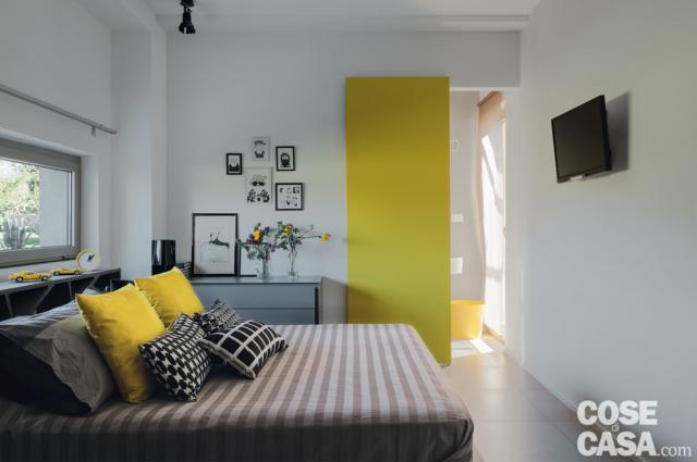camera matrimoniale, interni contemporanei, letto, copriletto rigato, cuscini gialli e quadrettati, porta scorrevole gialla, finestra a nastri, tv, cassettiera camera matrimoniale, interni contemporanei, letto, copriletto rigato, cuscini gialli e quadrettati, porta scorrevole gialla, finestra a nastri, tv, cassettiera