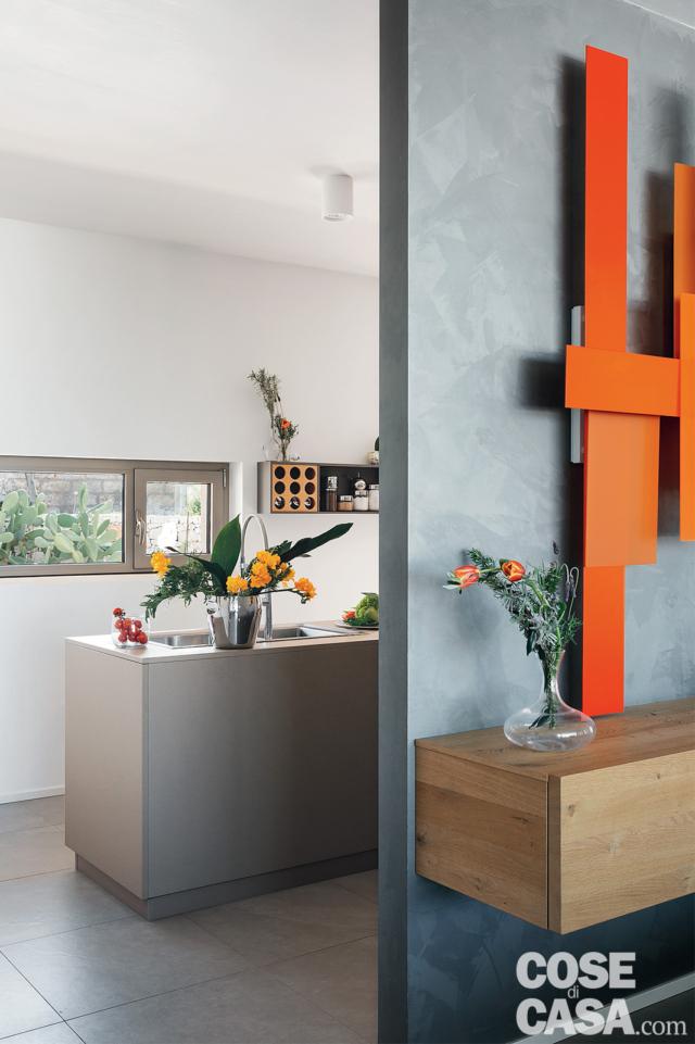 parete con finitura cemento, mobile sospeso, lampada modulare rossa, pavimento in lastre di gres grigie, cucina, finestra a nastro, bancone a isola, faretti parete con finitura cemento, mobile sospeso, lampada modulare rossa, pavimento in lastre di gres grigie, cucina, finestra a nastro, bancone a isola, faretti