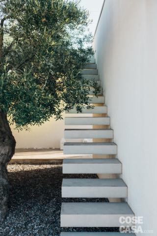 Come abbiamo visto la casa è stata costruita in anni recenti con interni contemporanei ma nel rispetto dell'ambiente naturale circostante. Il patio interno in posizione d'angolo, accessibile dall'open space del soggiorno, si rifà a uno degli elementi tipici delle vecchie dimore pugliesi nelle quali era considerato luogo privilegiato del vivere quotidiano. In questo caso lo spazio di circa 25 mq, pavimentato con ciotoli di ghiaia fine, è in gran parte occupato dalla scala che porta al lastrico solare e da un albero di ulivo che è stato così integrato nel nuovo contesto. La presenza di elementi caratterizzanti come gli ulivi secolari nella tenuta e la loro tutela ha vincolato sotto molti aspetti il progetto in quanto in base alla loro posizione è stata stabilita - in fase di progettazione - quella dell'immobile da costruire ex novo. Come abbiamo visto la casa è stata costruita in anni recenti con interni contemporanei ma nel rispetto dell'ambiente naturale circostante. Il patio interno in posizione d'angolo, accessibile dall'open space del soggiorno, si rifà a uno degli elementi tipici delle vecchie dimore pugliesi nelle quali era considerato luogo privilegiato del vivere quotidiano. In questo caso lo spazio di circa 25 mq, pavimentato con ciotoli di ghiaia fine, è in gran parte occupato dalla scala che porta al lastrico solare e da un albero di ulivo che è stato così integrato nel nuovo contesto. La presenza di elementi caratterizzanti come gli ulivi secolari nella tenuta e la loro tutela ha vincolato sotto molti aspetti il progetto in quanto in base alla loro posizione è stata stabilita - in fase di progettazione - quella dell'immobile da costruire ex novo.