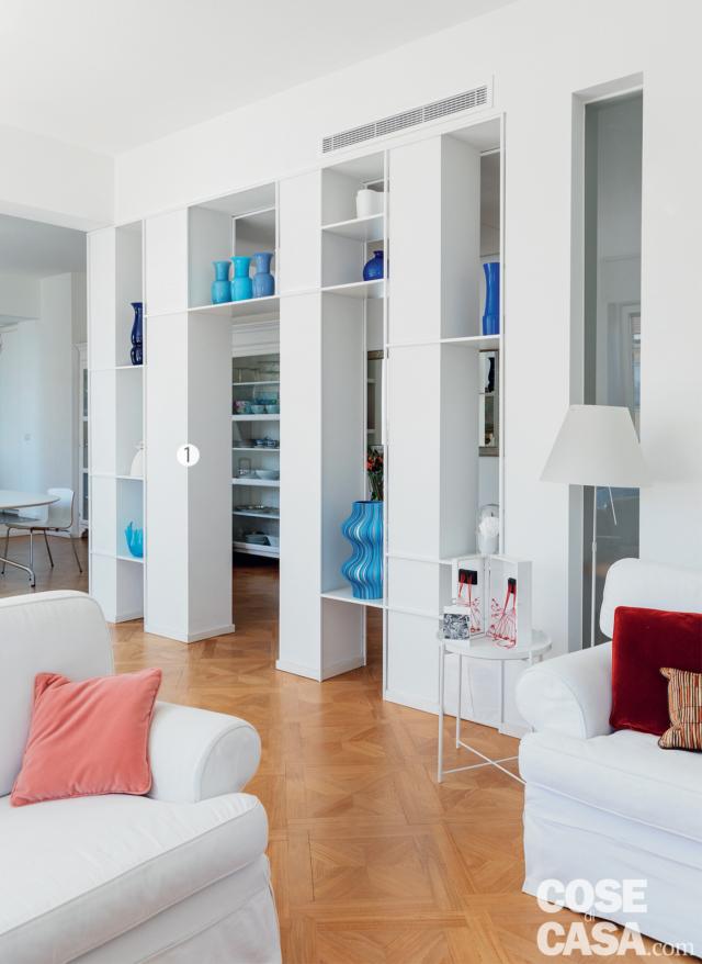 struttura passante in muratura, ingresso, soggiorno, colonnato, parquet in rovere con intarsi, tavolino rotondo, divani, lampada da terra, vasi di design sulle mensola, bocchetta dell'impianto canalizzato struttura passante in muratura, ingresso, soggiorno, colonnato, parquet in rovere con intarsi, tavolino rotondo, divani, lampada da terra, vasi di design sulle mensola, bocchetta dell'impianto canalizzato
