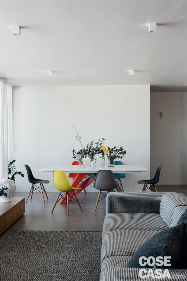 soggiorno, divano grigio, tappeto, zona pranzo, tavolo rettangolare con base rossa, sedie di design multicolori, faretti a soffitto soggiorno, divano grigio, tappeto, zona pranzo, tavolo rettangolare con base rossa, sedie di design multicolori, faretti a soffitto