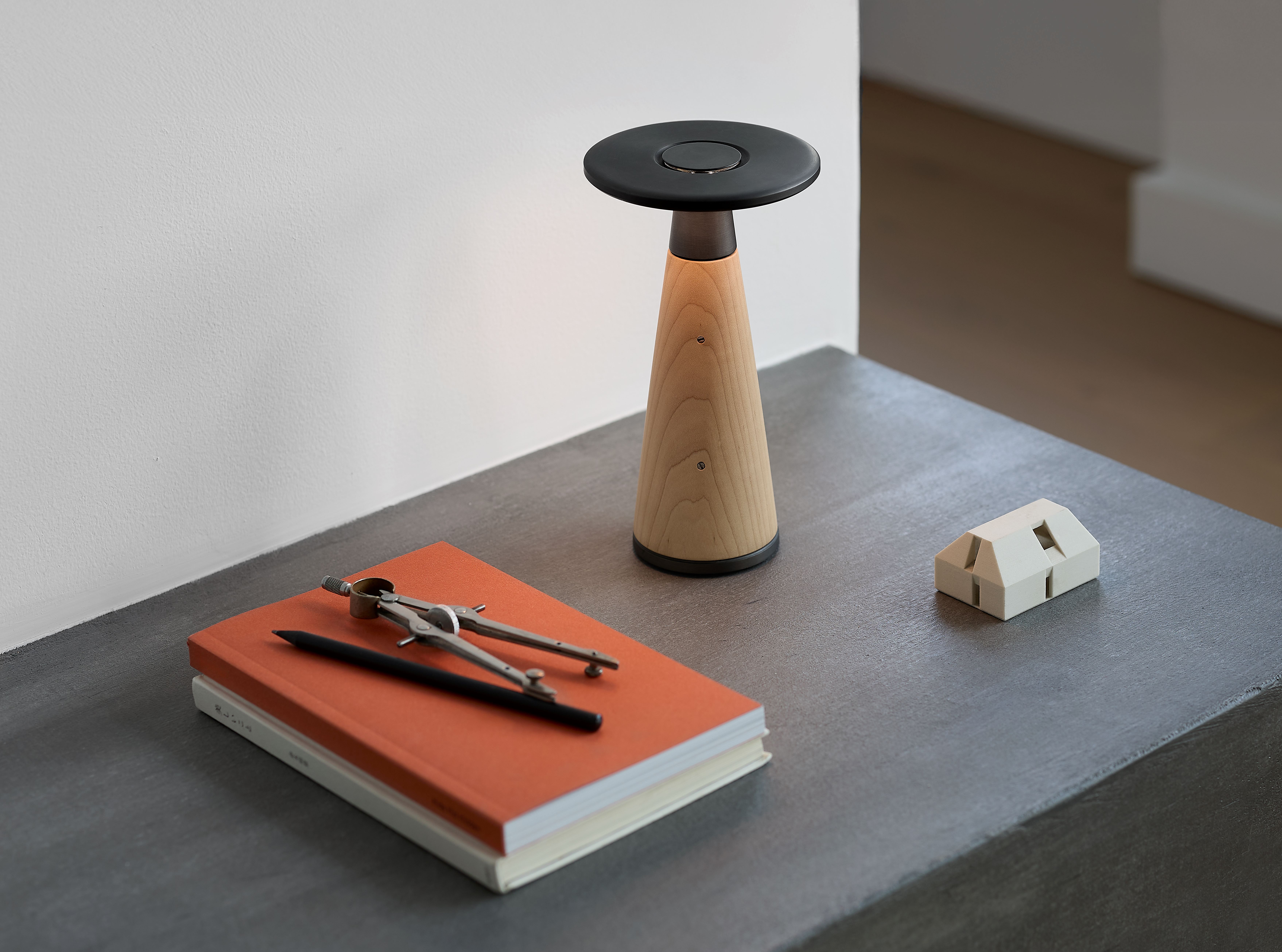 Vosco (design Nao Tamura) di Ambientec, ricaricabile, offre una luce uniforme e morbida grazie a una lente Fresnel, con 5 livelli di luminosità che variano dalla calda luce di una candela fino a 2400K, ideale per cena, lettura o relax. La parte centrale in legno può essere regolata in tre dimensioni e sostituita nel tempo, e il corpo è disponibile in noce, acero o rovere. www.ambientec.co.jp