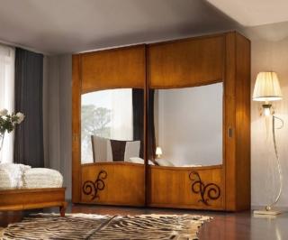Con specchi sagomati
Un classico rivisitato dalle linee geometriche impreziosito con decori che risaltano sulla superficie spazzolata, una finitura che evidenzia le venature del legno. Gli specchi dai profili sinuosi sono  supportati con pannello multistrato anti rottura. A 2 ante scorrevoli, in massello e listellare di frassino l'armadio Rif. 4103/240 di Il Mobile Classico Italiano misura L 291 x P 66 x H 247 cm. Costa 3.041 euro (comprese spese di spedizione). www.ilmobileclassicoitaliano.it