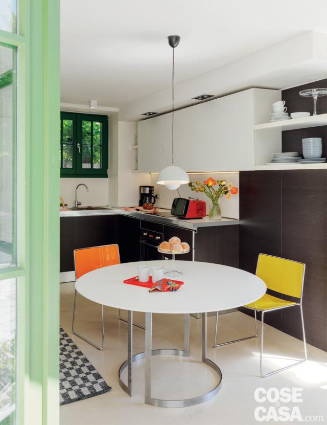 cucina, tavolo rotondo, sedie gialla e arancione, composizione su due lati, vasi in wengé, pensili in laccato bianco, mensole, tv anni '60, lampada a sospensione, finestra, passatoia cucina, tavolo rotondo, sedie gialla e arancione, composizione su due lati, vasi in wengé, pensili in laccato bianco, mensole, tv anni '60, lampada a sospensione, finestra, passatoia