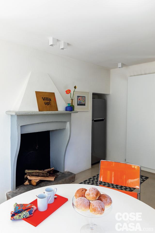 zona pranzo, tavolo rotondo, sedia arancione, camino in muratura, faretti a soffitto, frigorifero freestanding in nicchia, radiatore a piastra bianco zona pranzo, tavolo rotondo, sedia arancione, camino in muratura, faretti a soffitto, frigorifero freestanding in nicchia, radiatore a piastra bianco