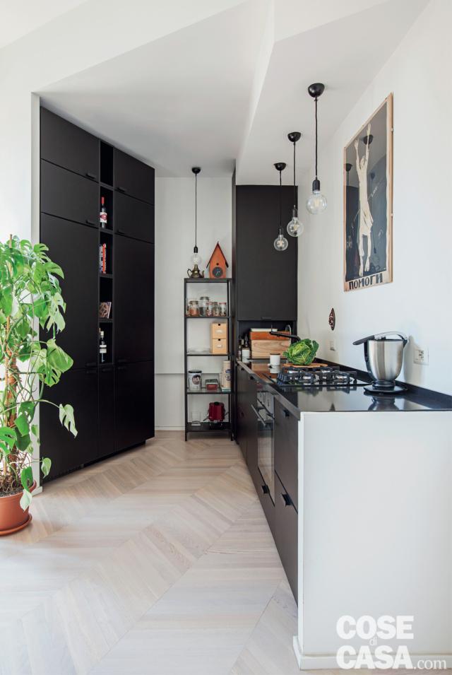 zona cottura, pareti oblique, muretto, basi in finitura scura, lampade a sospensione, armadiatura con dispensa, mobile a ripiani, controsoffitto, parquet a spina di pesce zona cottura, pareti oblique, muretto, basi in finitura scura, lampade a sospensione, armadiatura con dispensa, mobile a ripiani, controsoffitto, parquet a spina di pesce