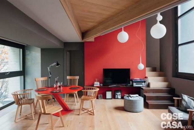 zona pranzo, tavolo rotondo di design, sedie in legno, vetrata, parete rossa, zona tv, scala, lampade a sospensione sferiche, pouf, soffitto in legno zona pranzo, tavolo rotondo di design, sedie in legno, vetrata, parete rossa, zona tv, scala, lampade a sospensione sferiche, pouf, soffitto in legno