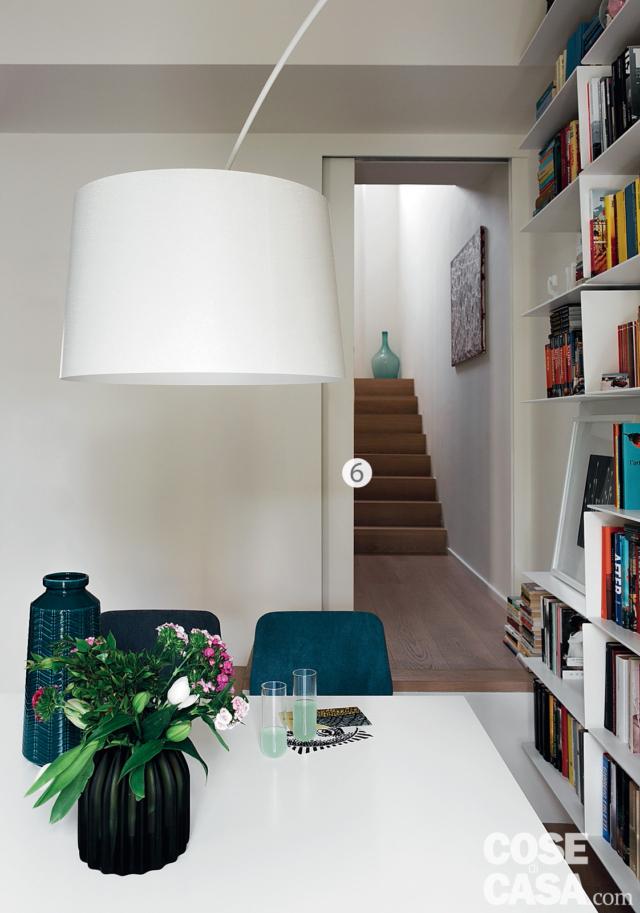 zona giorno, tavolo da pranzo bianco, sedie blu, lampada ad arco, libreria a giorno, porta scorrevole, rampa con gradini in legno zona giorno, tavolo da pranzo bianco, sedie blu, lampada ad arco, libreria a giorno, porta scorrevole, rampa con gradini in legno