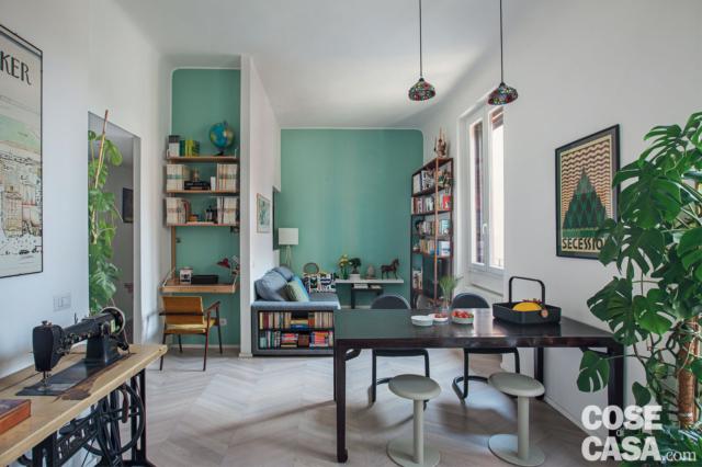 zona giorno del bilocale di 60 mq, postazione studio in nicchia, tavolo da pranzo nero, sedie, sgabelli bianchi, macchina per cucire vintage, pavimento in parquet, pareti tinteggiate in verde, lampade a sospensione zona giorno del bilocale di 60 mq, postazione studio in nicchia, tavolo da pranzo nero, sedie, sgabelli bianchi, macchina per cucire vintage, pavimento in parquet, pareti tinteggiate in verde, lampade a sospensione