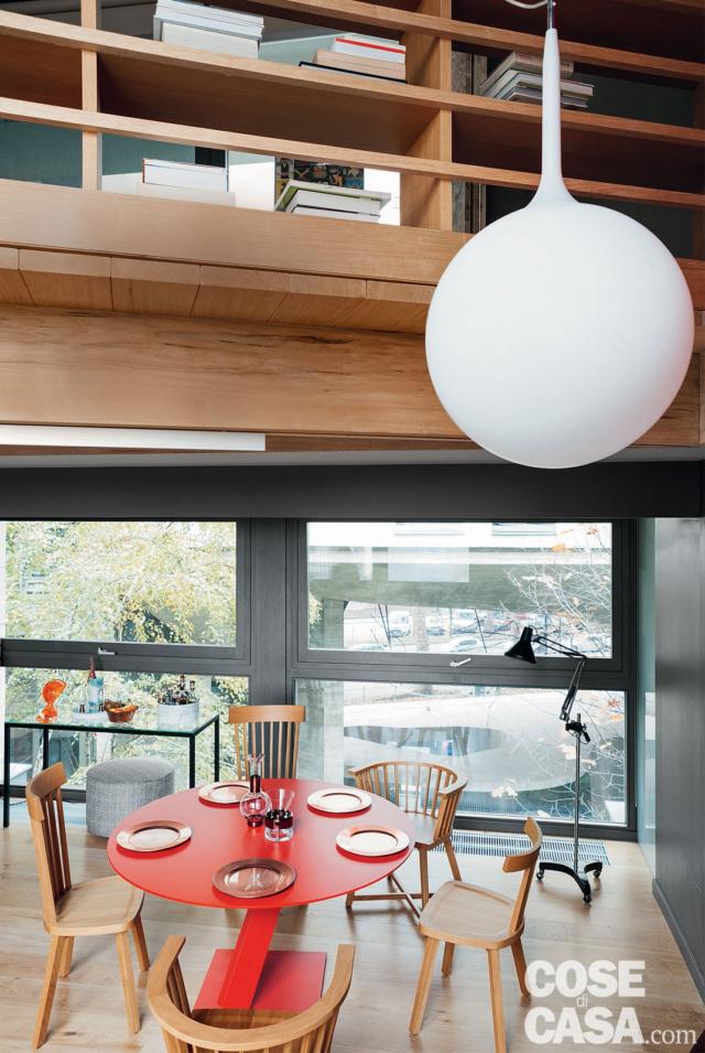 libreria-balaustra in legno, vetrate, zona pranzo, tavolo rotondo di design, sedie in legno, lampada da terra su ruote, pavimento in parquet libreria-balaustra in legno, vetrate, zona pranzo, tavolo rotondo di design, sedie in legno, lampada da terra su ruote, pavimento in parquet