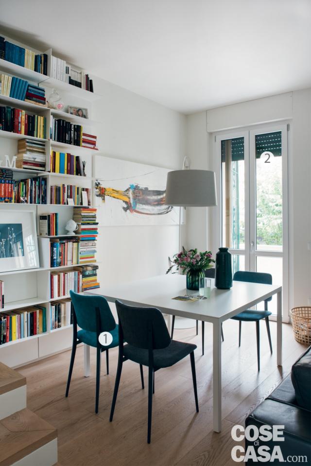 zona giorno della casa su due livelli, tavolo da pranzo rettangolare, sedie azzurre, lampada a sospensione, libreria a giorno di design, portafinestra con tapparella, pavimento in parquet zona giorno della casa su due livelli, tavolo da pranzo rettangolare, sedie azzurre, lampada a sospensione, libreria a giorno di design, portafinestra con tapparella, pavimento in parquet