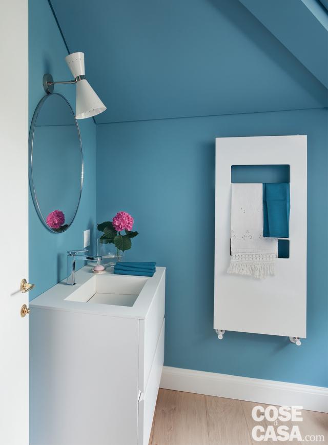 bagno, parete azzurra, scaldasalviette bianco, mobile con lavabo integrato, specchio tondo, applique a megafono, zoccolino bianco, pavimento in parquet bagno, parete azzurra, scaldasalviette bianco, mobile con lavabo integrato, specchio tondo, applique a megafono, zoccolino bianco, pavimento in parquet
