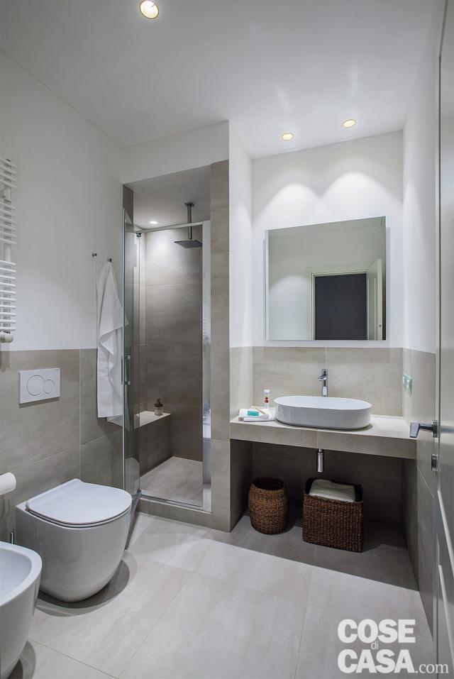 bagno del grande appartamento, box doccia in muratura, sanitari, rivestimenti in gres grigio, piano sospeso in muratura, lavabo da appoggio, specchio, faretti, porta bagno del grande appartamento, box doccia in muratura, sanitari, rivestimenti in gres grigio, piano sospeso in muratura, lavabo da appoggio, specchio, faretti, porta