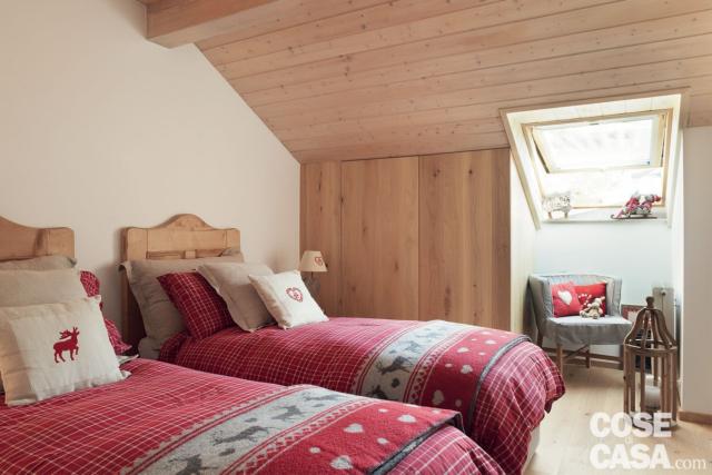 tetto a spiovente rivestito in legno, camera della mansarda rinnovata,letti singoli, copriletti rossi ricamati, poltroncina, lucernario tetto a spiovente rivestito in legno, camera della mansarda rinnovata,letti singoli, copriletti rossi ricamati, poltroncina, lucernario