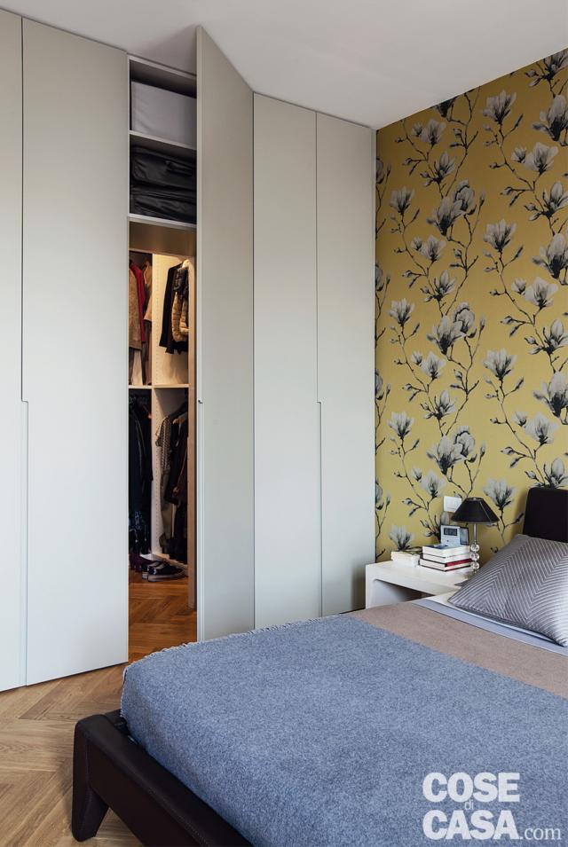 camera matrimoniale, armadio su misura in laccato bianco, letto in pelle, comodino bianco, parete rivestita con carta da parati gialla con fiori, copriletto azzurro camera matrimoniale, armadio su misura in laccato bianco, letto in pelle, comodino bianco, parete rivestita con carta da parati gialla con fiori, copriletto azzurro