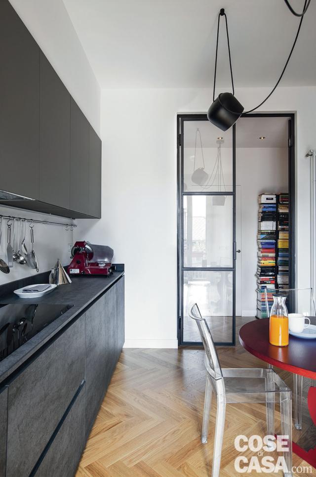 cucina, composizione in finitura antracite, parquet a spina di pesce, porta vetrata industrial, lampada di design, tavolo rotondo rosso, sedia in policarbonato trasparente cucina, composizione in finitura antracite, parquet a spina di pesce, porta vetrata industrial, lampada di design, tavolo rotondo rosso, sedia in policarbonato trasparente